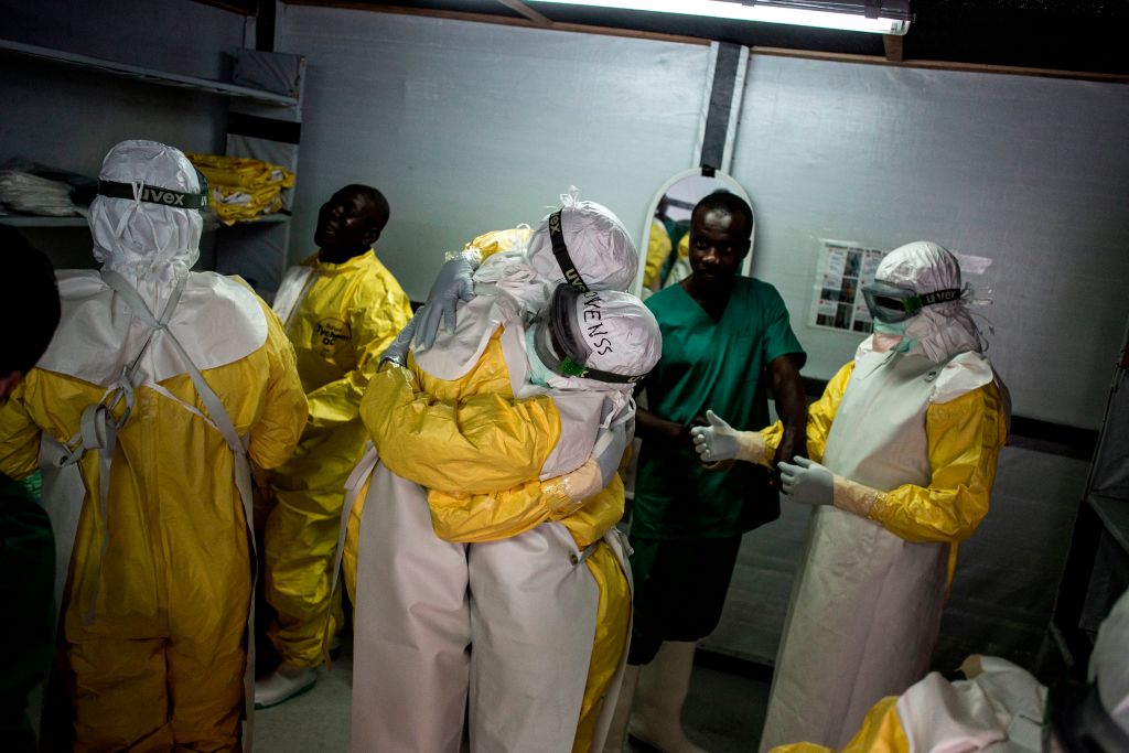 Health workers embrace while putting on their personal protective equipment