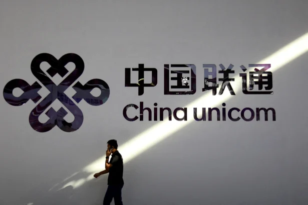A man holding a mobile phone walks past a China Unicom logo during the Mobile World Congress in Shanghai, China, on June 28, 2023. (Nicoco Chan/Reuters)