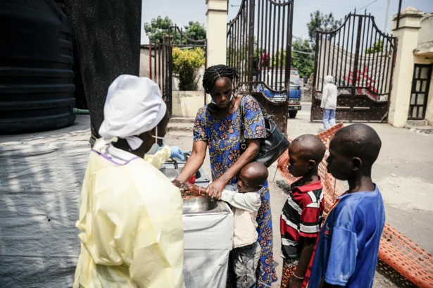 A mother helps her children wash their hands before entering Kyeshero Hospital at a checkpoint for handwashing and temperature screening for all visitors and patients, as part of Ebola prevention measures in Goma on May 18, 2026. (Jospin Mwisha/AFP via Getty Images)
