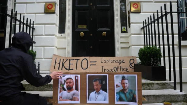 A protester places photos of three men charged with assisting Hong Kong's foreign intelligence service in the UK on the door of the Hong Kong Economic and Trade Office, in London on May 14, 2024. (Toby Melville/Reuters)