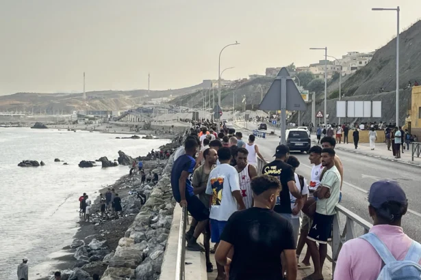 Crowds of young Moroccan migrants gather along the coastal road near Avenida Martínez Catena in the Spanish territory of Ceuta, in Spain, on July 31, 2026, after swimming across from Morocco. (Etienne Fauchaire/The Epoch Times)